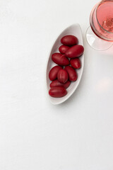 Burgundy olives in a white bowl. Glass with red wine. Copy space.