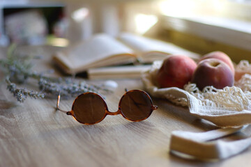 Mesh tote with fresh peacehs, lavender bouquet, round sunglasses, vintage book and seashell on the table. Selective focus.
