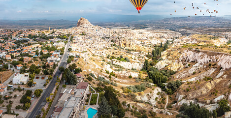 The rolling hills of Cappadocia's Pigeon Valley framed by the imposing Uchisar Castle create an awe-inspiring image with hot air flying balloons