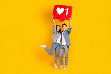 Full length photo of sweet adorable couple dressed denim rising big like heart pinata isolated yellow color background