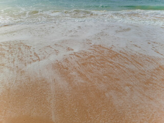 Beautiful sand beach and turquoise water. Summer holiday beach background. Ocean waves on empty tropical sand beach. Vertical background