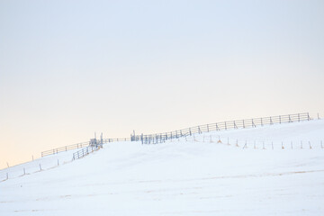 Fences on a snowy hillside in dawn winter landscape - Powered by Adobe