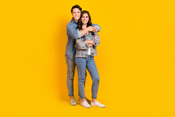 Full length photo of cute adorable young husband wife dressed denim embracing smiling isolated yellow color background