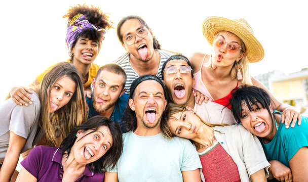 Multicultural mixed age people taking selfie sticking out tongue making funny faces - Crazy life style and integration concept with interracial young friends having fun together - Bright vivid filter