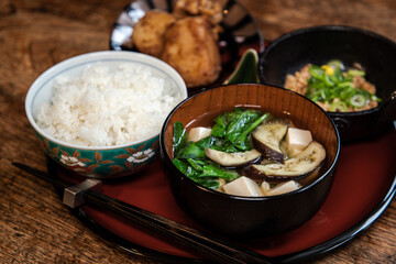 茄子とほうれん草と絹ごし豆腐のお味噌汁とご飯とひきわり納豆とお芋とお揚げの味噌和えの和食の朝ごはん