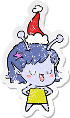 happy alien girl distressed sticker cartoon of a wearing santa hat