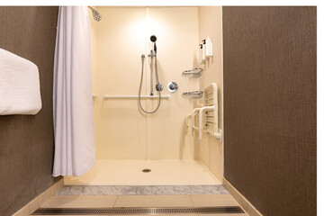 Wheelchair accessible hotel bathroom shower with tile floor and walls.