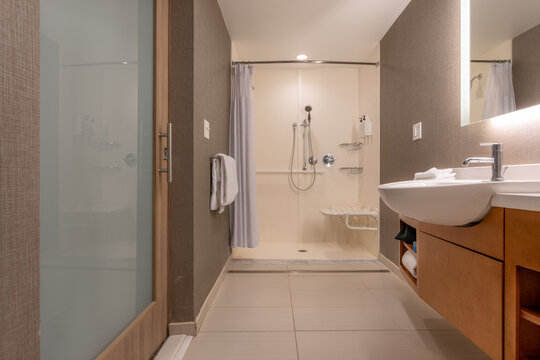 Wheelchair accessible hotel bathroom shower with tile floor and walls.