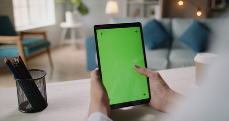 Close up shot of hands holding a tablet computer with mock up chroma key green screen. Template for online education and video conferences 