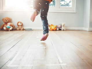 Hopscotch, happy and feet of child play in home having fun, enjoying games and entertainment in...