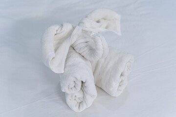Fototapeta na wymiar Beautifully folded clean white bath towels set folding fabric into elephant shape on the bed neatly clean bed of the hotel room coziness textile the hotel.