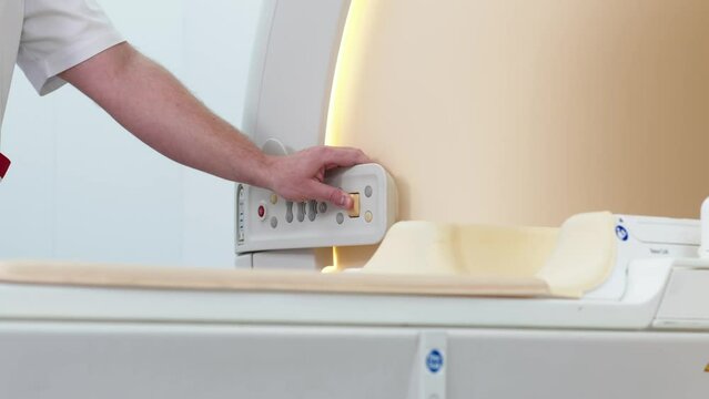 A doctor performs an MRI or PET scan of a patient in a modern clinic. Magnetic resonance imaging in the study of the human body. The doctor prepares the apparatus for computed tomography