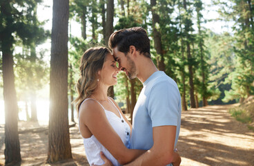 Hug, happy and an affectionate couple in nature for peace, relaxation and date in the forest. Smile, embrace and a young man and woman hugging for love, care and affection on a vacation in the woods