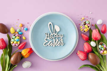 Easter sweets idea. Top view photo of blue plate and inscription happy easter chocolate eggs with сolorful candies butterfly cookie and tulips flowers on pastel violet background