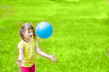 Obraz premium Young girl with syndrome down plays with a ball in a summer park. Empty space for text
