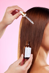 Closeup, woman and hair care with oil, pipette and luxury salon treatment against a studio...