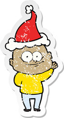 distressed sticker cartoon of a bald man staring wearing santa hat