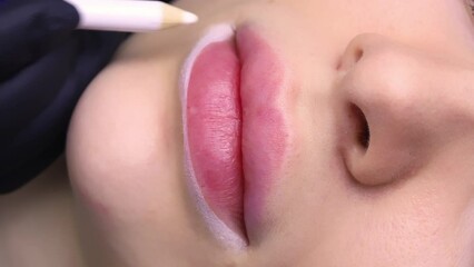 A close-up of the lips of a young and beautiful girl who is undergoing a permanent lip makeup procedure.. High quality 4k footage