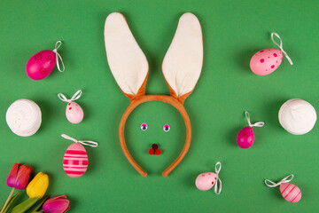 Comical Easter backdrop in shades of green, showcasing pink eggs and a bunny face