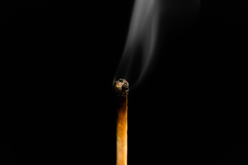 A lit match with smoke on a black background, macro photography. An extinguished match with smoke.