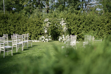 Beautiful Wedding ceremony event. Outdoor wedding arch. Green and white wedding decorations. Wedding day.