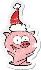 cheerful sitting pig distressed sticker cartoon of a wearing santa hat