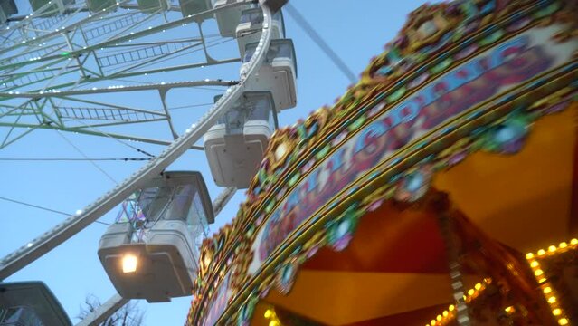 Carousel spinning in front of the Ferris wheel. Panorama from right to left