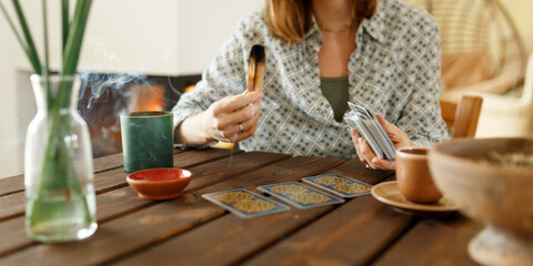 Fortune teller with tarot cards on table near burning candle.Tarot cards spread on table with magic...