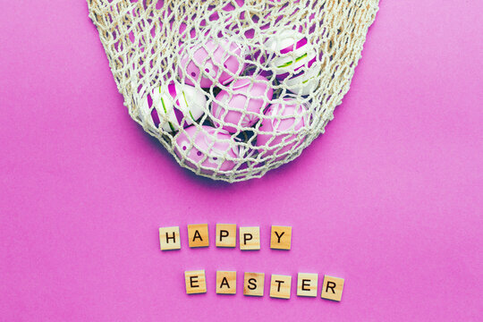 Happy easter with colorful painted eggs and cotton string bag on pink background