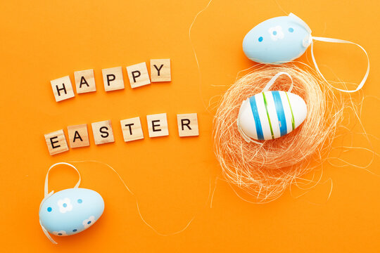colorful handmade painted eggs in the nest on orange background