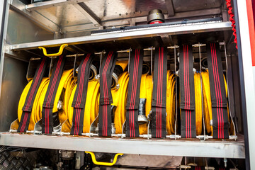 Compartment of rolled up fire hoses on a fire engine. Rescue fire truck equipment. Close up.