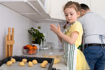 child help to father in kitchen. kid cooking food with dad. little girl, man in apron making dough, baking pie, cookies, making biscuit. family together home at stove, oven