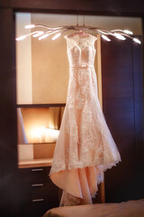 Bride's dress. Beautiful bridesmaid dress. Bride morning. Wedding. Married Dress on a hanger. The dress hangs on a chandelier. Fashion
