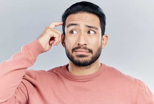 Thinking, question and doubt with a man in studio on a gray background looking thoughtful or contemplative. Confused, idea and memory with a young asian male trying to remember but feeling unsure