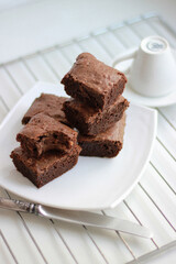 Homemade chocolate brownies stacked on a white plate, side and top view. Close-up.