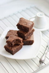 Close-up homemade chocolate brownies stacked on a white plate, side and top view. 