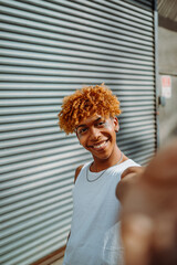 Vertical view of the teenager multiracial guy smiling confident while making selfie by the camera