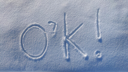 The inscription o'k on the white snow on a cold winter sunny day. The concept all will be well