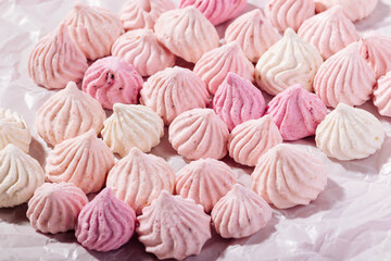 Pink meringue cookies with berry flavor on baking parchment