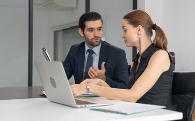 Businessman consulting business inquiries with female secretary on laptop and looking at document...