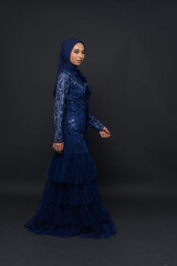 Naklejka premium A teenager model use blue dress. She's pose in the studio indoor. She's pose in dark gray background with elegant pose. She's look like beautiful and graceful 