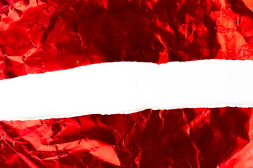 Crumpled red aluminum foil is torn apart in the middle on a white background for pasting text.