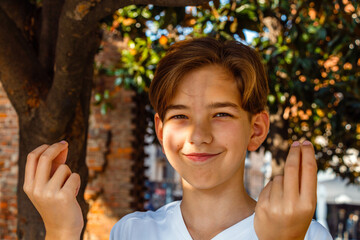 Teenage boy doing italian gestures with his hands and smiling under the tree