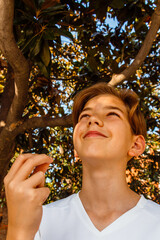 Teenage boy doing italian gesture with his hand and smiling under the tree