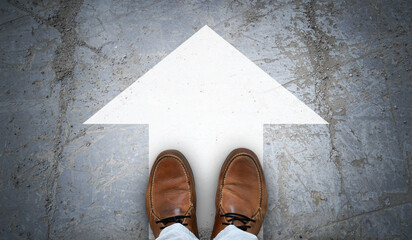 Brown leather shoes and chalky arrow on asphalt - forward concept