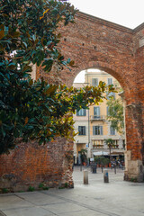 Building behind a brick arch and a tree