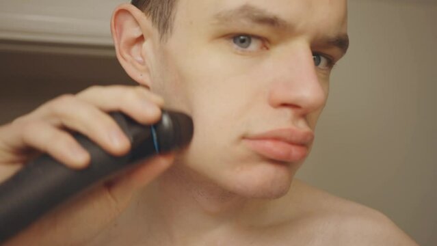 Man Shaving Using Electric Shaver. Close Up