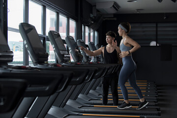 Fototapeta person exercising in gym. woman exercising in gym. Sportswoman on training while running on treadmill machine in the gym. Happy and positive people workout. obraz