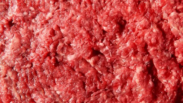 Top view of raw minced meat with onion, garlic and spice. Raw red forcemeat background. Full frame of spicy mince is rotating, spinning. Juicy beef and pork mincemeat. Stuffing meat with seasoning.