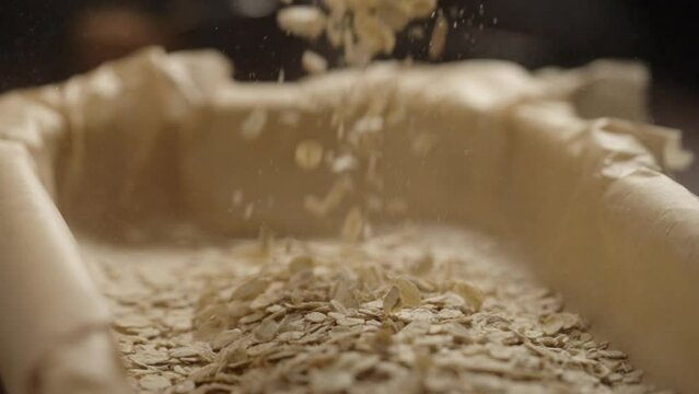 Slow motion making granola in baking tray, oats pour